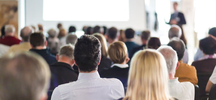 corporate event attendees sit and watch a presentation 